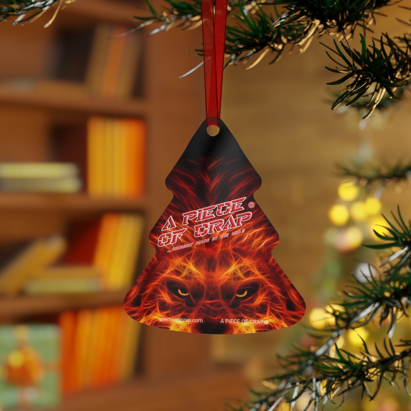 A round metallic charm with a glossy finish, featuring a text and a graphic of a lion's face, hanging from a red ribbon.