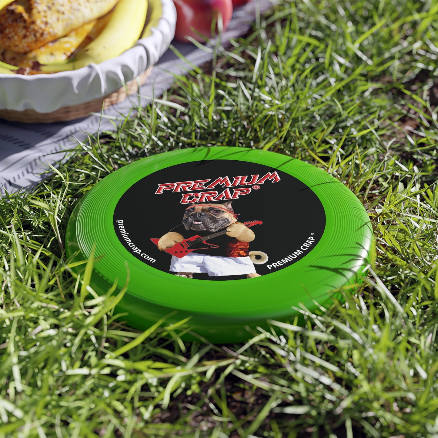 A green Wham-O Frisbee with a logo and text on it, sitting on grass.