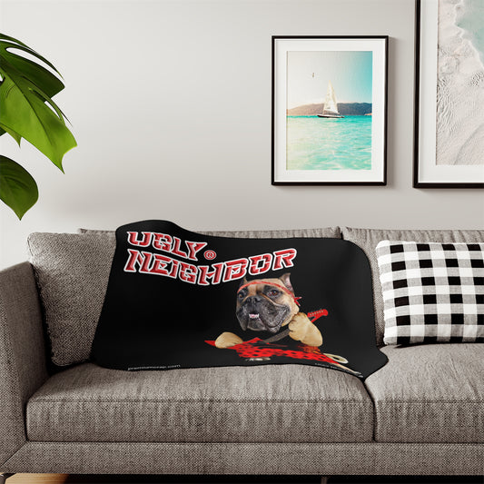 Black blanket with a dog graphic and 'Ugly Neighbor' text on a gray couch.