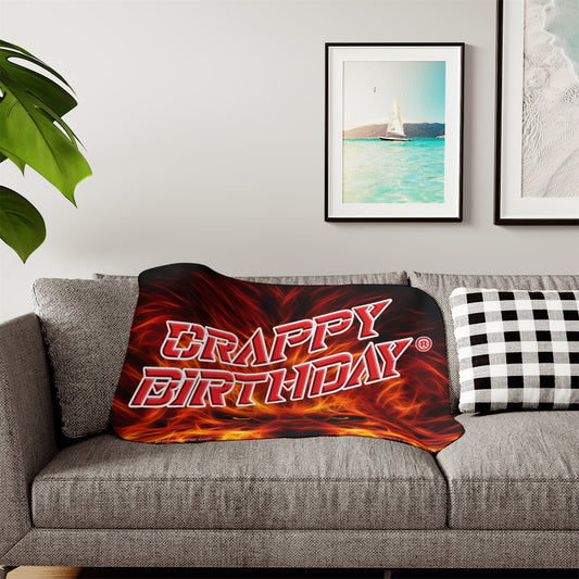 Sherpa Blanket with 'Crappy Birthday' text on a gray sofa in a living room setting.