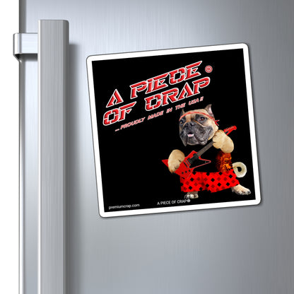 A square refrigerator magnet featuring a humorous graphic with the text 'A PIECE OF CRAP' and a bulldog in a red polka-dot dress playing a guitar, shown attached to a silver metal refrigerator door.