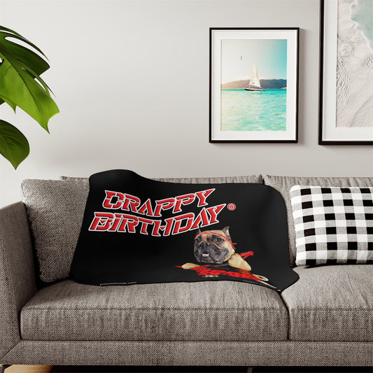 Black blanket with 'Crappy Birthday' text and a dog graphic draped over a gray sofa.