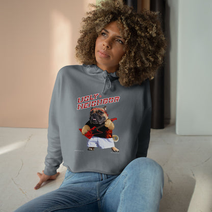 Woman wearing a hoodie with 'Ugly Neighbor' graphic sitting on a light-colored floor.