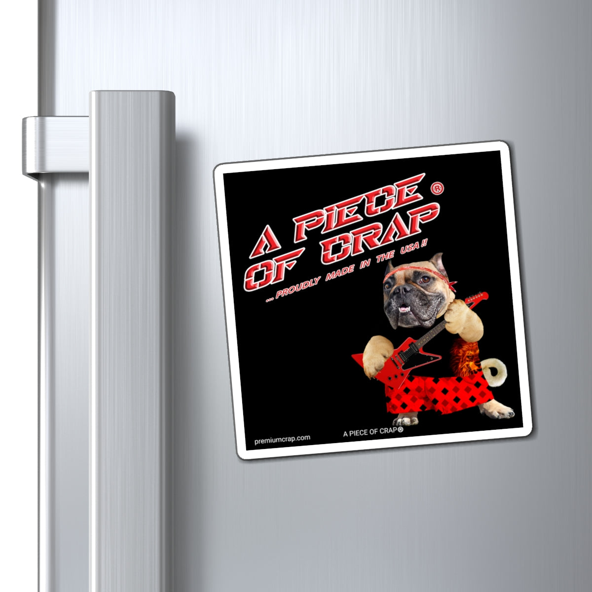 A square refrigerator magnet with a black background and a cartoon dog wearing red shorts, attached to a brushed stainless steel refrigerator door next to the handle.