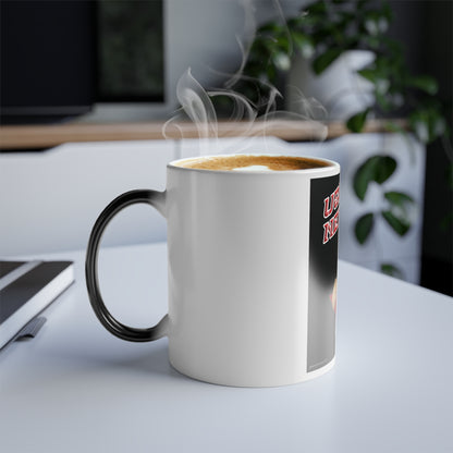A white ceramic coffee mug with a black handle sits on a white desk, filled with a steaming latte.