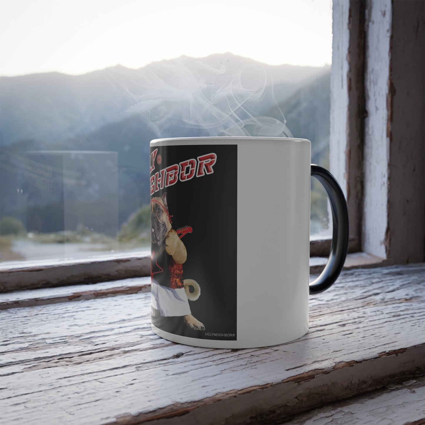 A white ceramic mug with a black handle sits on a weathered wooden windowsill, with steam rising from the mug and a blurred mountain landscape visible outside.