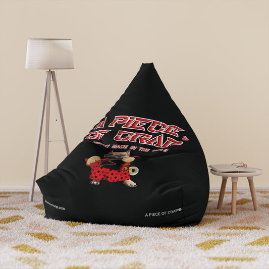 A black bean bag chair cover with text and a graphic on it, placed on a carpeted floor next to a tripod lamp and a small wooden table.