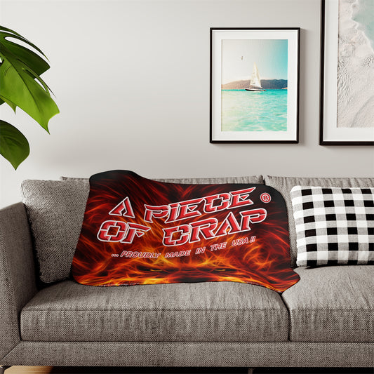 Flame-themed blanket with text on a gray sofa in a living room setting.